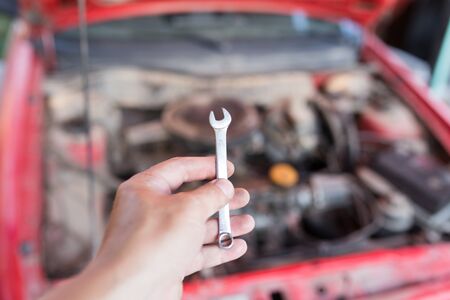 Wrench in hand on the background of carsの写真素材