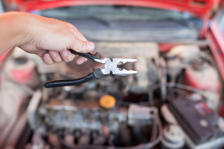 Pliers in hand on the background of carsの写真素材