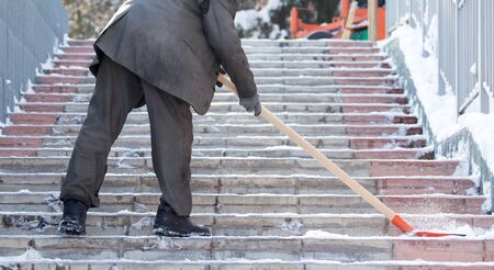Worker cleans snow shovel in the nature