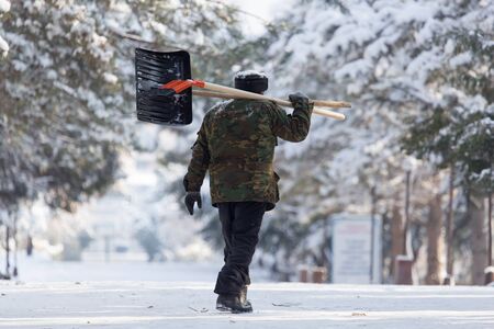 Worker cleans snow shovel in the natureの写真素材