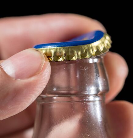 glass bottle with a cap in his hand on a black background