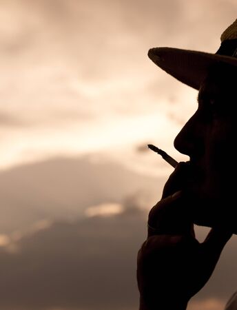 silhouette of a man smoking a cigarette on the sunset backgroundの写真素材