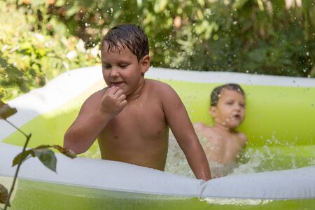 two boys poured water from the pool in natureの写真素材