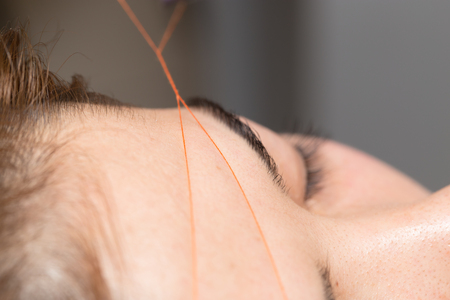 Grooming the eyebrows thread in a beauty salon. closeの写真素材