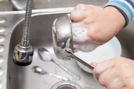 boy washing dishes in the kitchenの写真素材