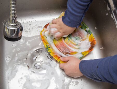 boy washing dishes in the kitchenの写真素材