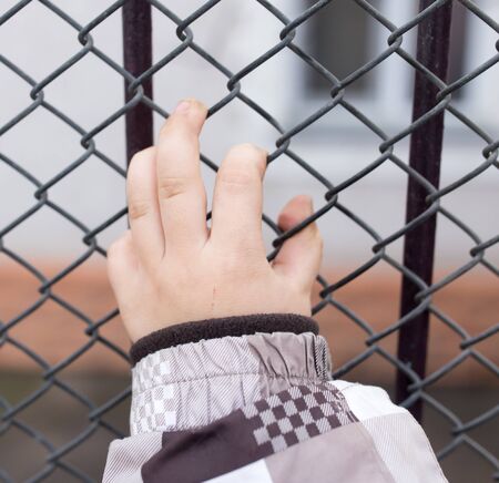 children's hands on a metal fenceの写真素材