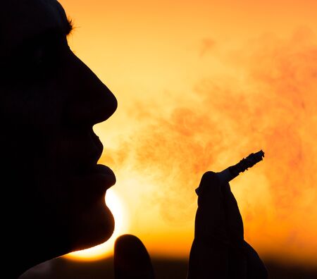 Silhouette of male smokers in the sunset