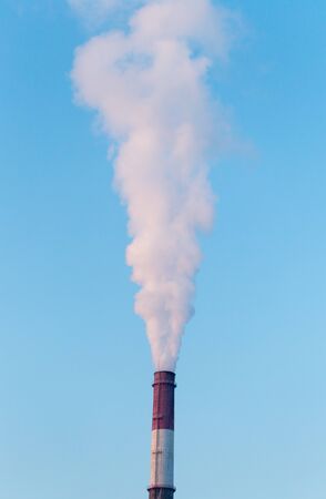 white industrial smoke from the chimney on a blue skyの写真素材