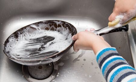 boy washing dishes in the kitchenの写真素材
