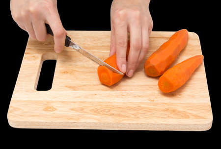 cook cuts carrots on a board on a black background .