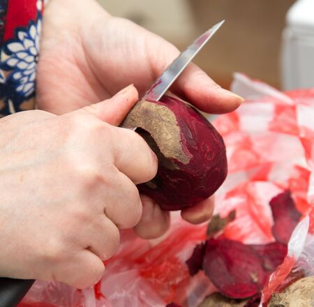 The chef cleans the red beet with a knife .の写真素材