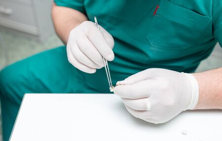 A dentist prepares an implant in the clinic .