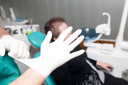 Doctor dentist puts on white gloves in the clinic .の写真素材