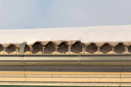 Icicles on the roof of the house at sunset .の写真素材