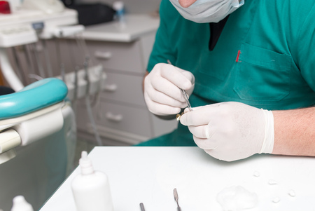A dentist prepares an implant in the clinic .