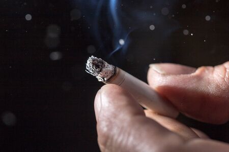Cigarette smokes in hand on a black backgroundの写真素材