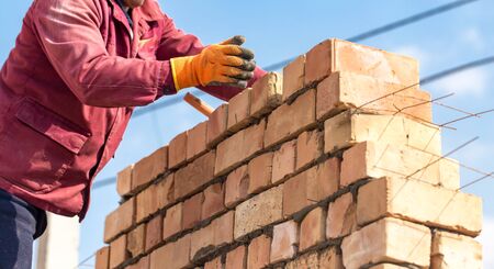 Worker builds a brick wall in the house .