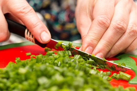 Cook cuts green onions with a knife .