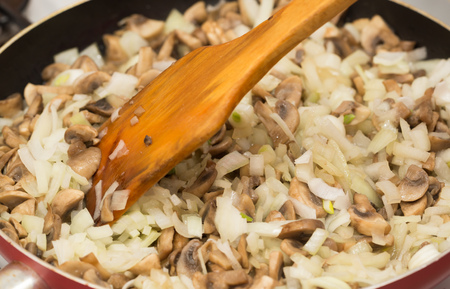 Mushrooms with onions are fried in a frying pan .の写真素材