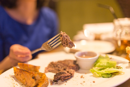 Girl eating meat with salad in a restaurant .の写真素材