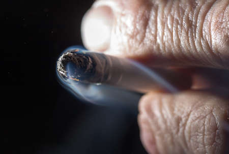 Cigarette smokes in hand on a black backgroundの写真素材