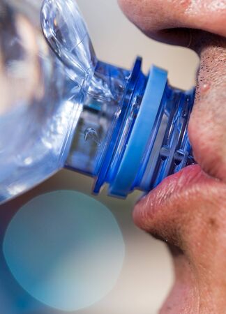 Man drinks water from a plastic bottle .