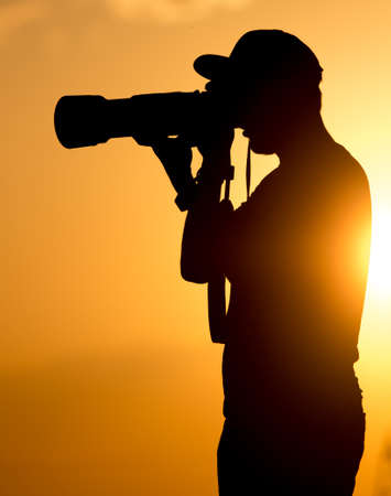 Man photographer with a camera at sunset .