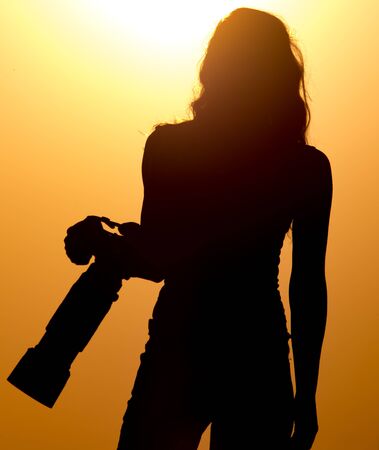 Silhouette of a girl photographer at sunset .の写真素材
