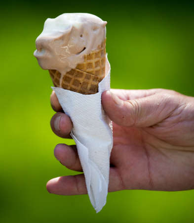 Ice cream in a waffle cup in a hand .