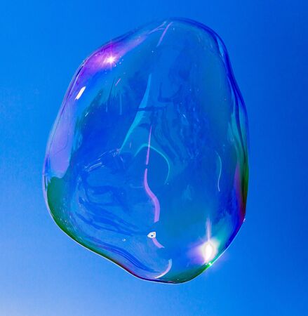 Big soap bubble against the blue sky .