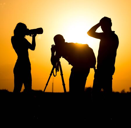 Silhouettes of people with cameras at sunset .の写真素材