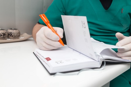 The doctor writes in a notebook at the clinic .の写真素材