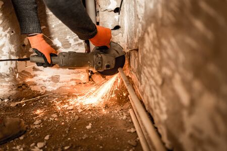 Worker cuts a metal pipe with sparks .
