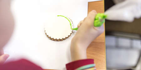 Girl decorates cookies with paint on the tableの写真素材