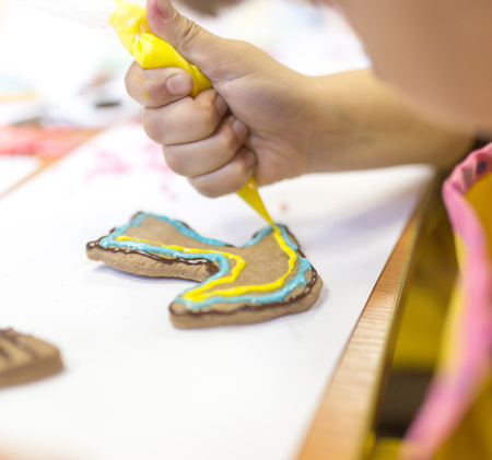 Girl decorates cookies with paint on the tableの写真素材