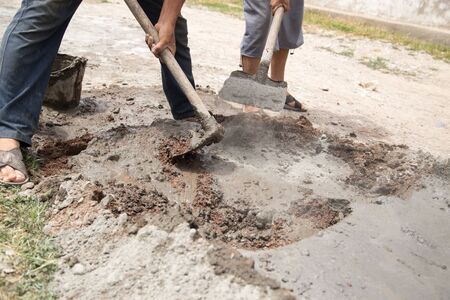 Worker mixes concrete with a shovel at the construction siteの写真素材