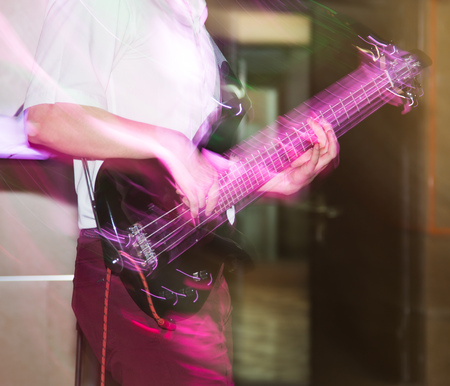 Musician playing guitar in a rock band .