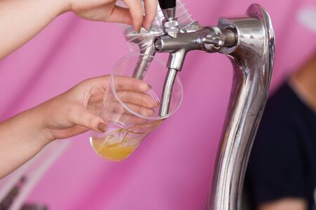 Barman pours beer into a plastic glass .の写真素材