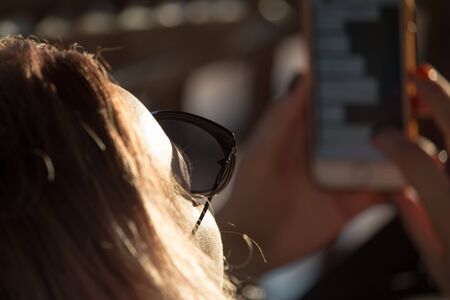 Girl in glasses from the sun with phone .の写真素材