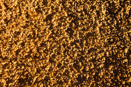 Plaster on a wall in gold lighting as a background .の写真素材