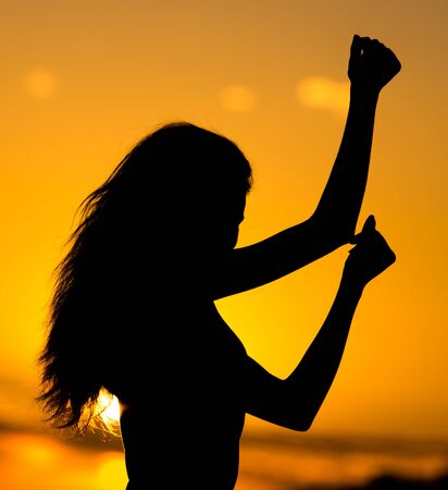 Silhouette of a girl with long hair at sunset .の写真素材