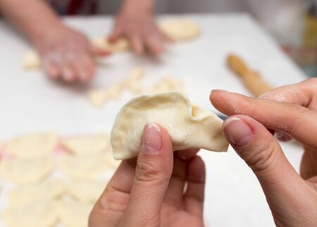 Cook cooks vareniki with potatoes in the kitchenの写真素材