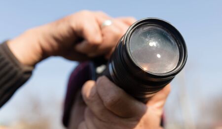 A large lens in the camera of a man .