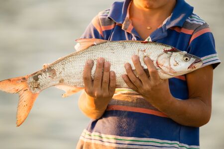 fisherman with a fish in the sunsetの写真素材