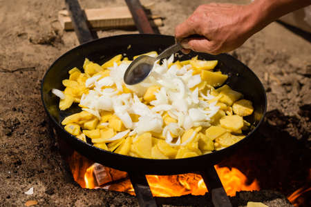 Potatoes fried in a frying pan in the open airの写真素材