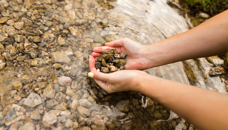 Small stones in the hand on the pondの写真素材