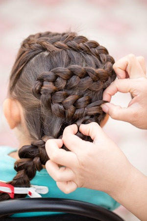 the stylist weaves the female braids on the headの写真素材