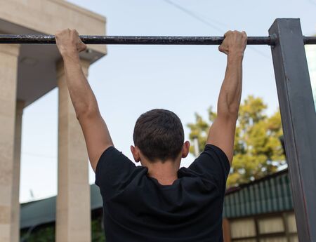the man pulls himself up on the bar