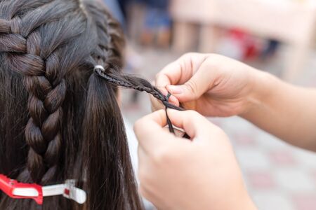 the stylist weaves the female braids on the headの写真素材